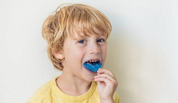 Child placing blue mouthguard