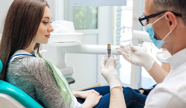 Dentist showing patient dental implant model