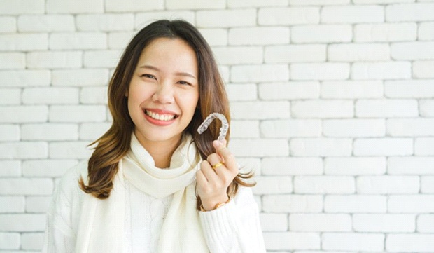 girl holding Invisalign clear aligner