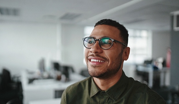 person at work sitting on a desk and smiling