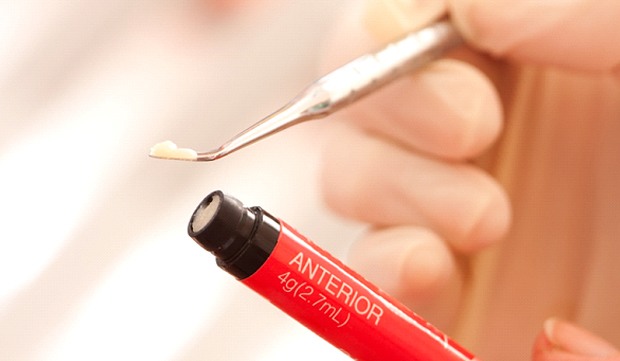 dentist holding a small tube of composite resin