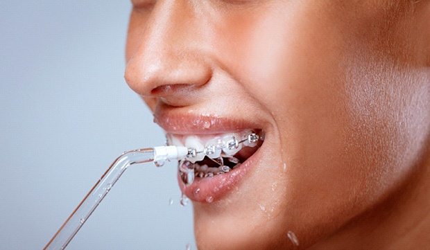 A woman using an oral irrigator to floss her teeth