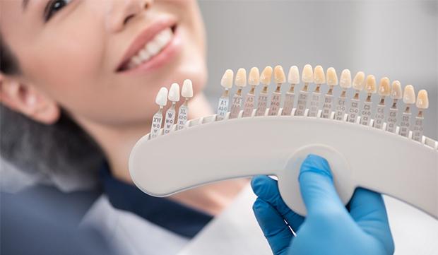 A dentist using a shade guide while talking to a female patient