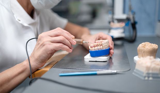 A dental lab technician creating veneers