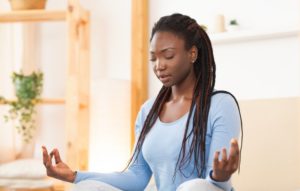 Woman in blue shirt with long hair meditating 